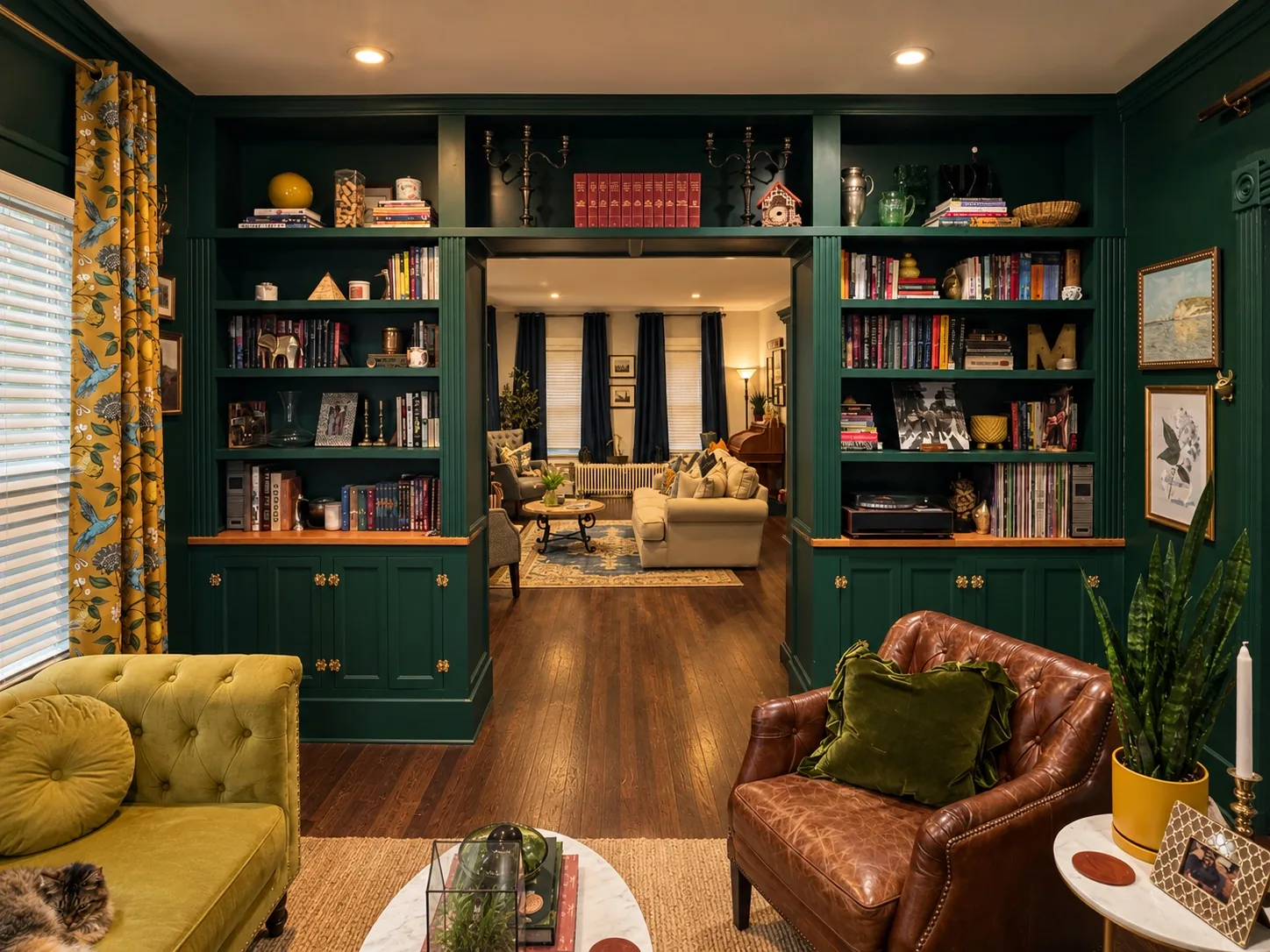 The finished deep-green library with custom built-ins, a mustard sofa and leather chairs