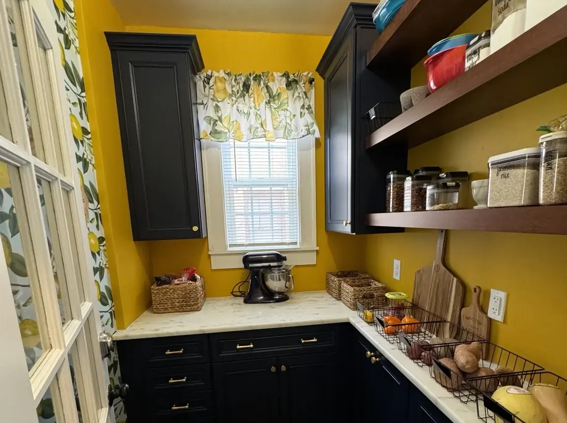The finished pantry with yellow walls, dark blue cabinetry, brass hardware and lemon details