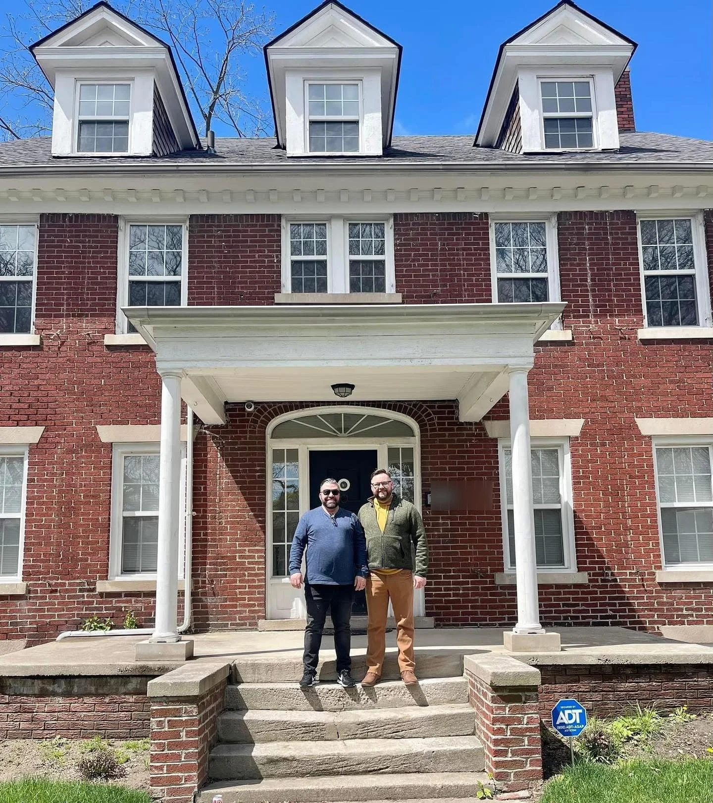 Steve and CJ standing together on the front porch of their 1919 Detroit home