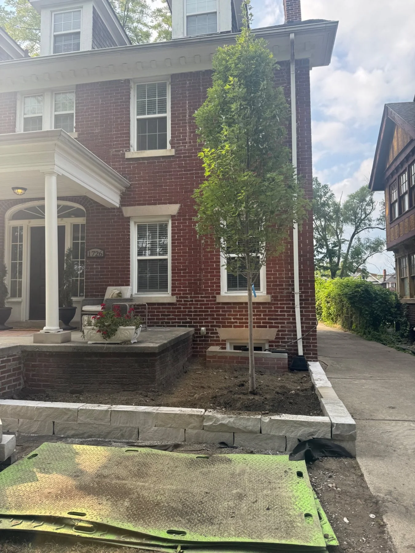 New tree planted beside the house with stone edging underway