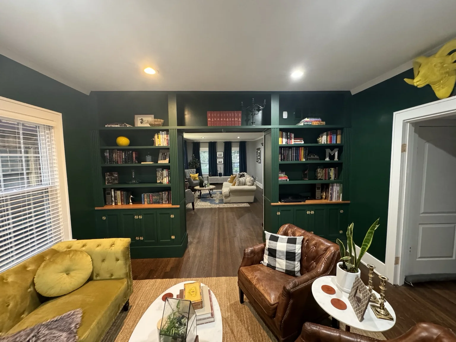 Finished and fully styled library with books and collected objects filling the custom green built-ins