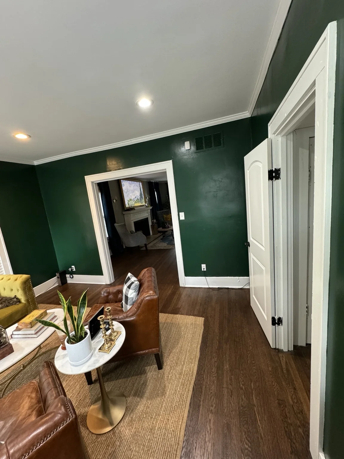Early furnished library in deep green with mustard sofa and leather chairs
