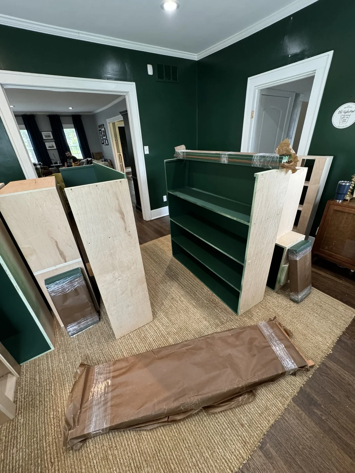 Painted green library built-in pieces staged in the room before installation