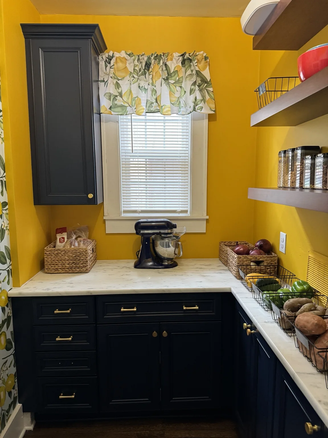 Finished pantry with stand mixer, baskets, dark cabinetry, and lemon details