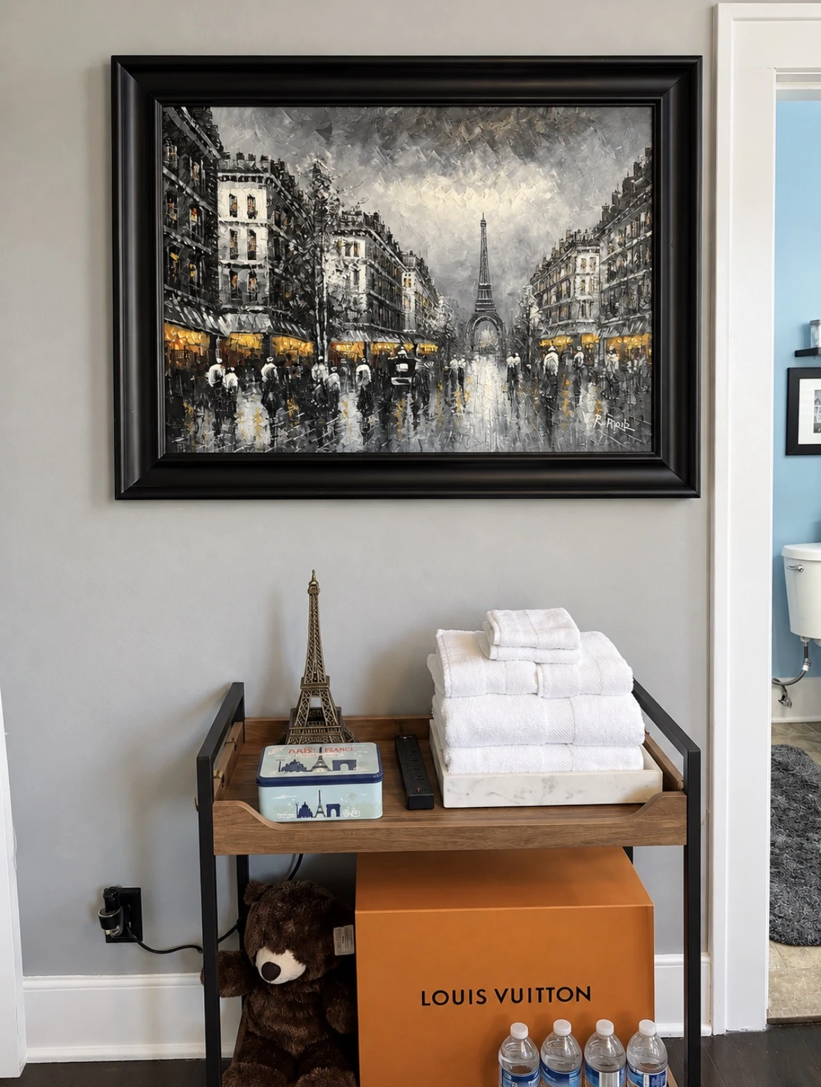 Framed Paris street painting above the wooden guest amenities cart