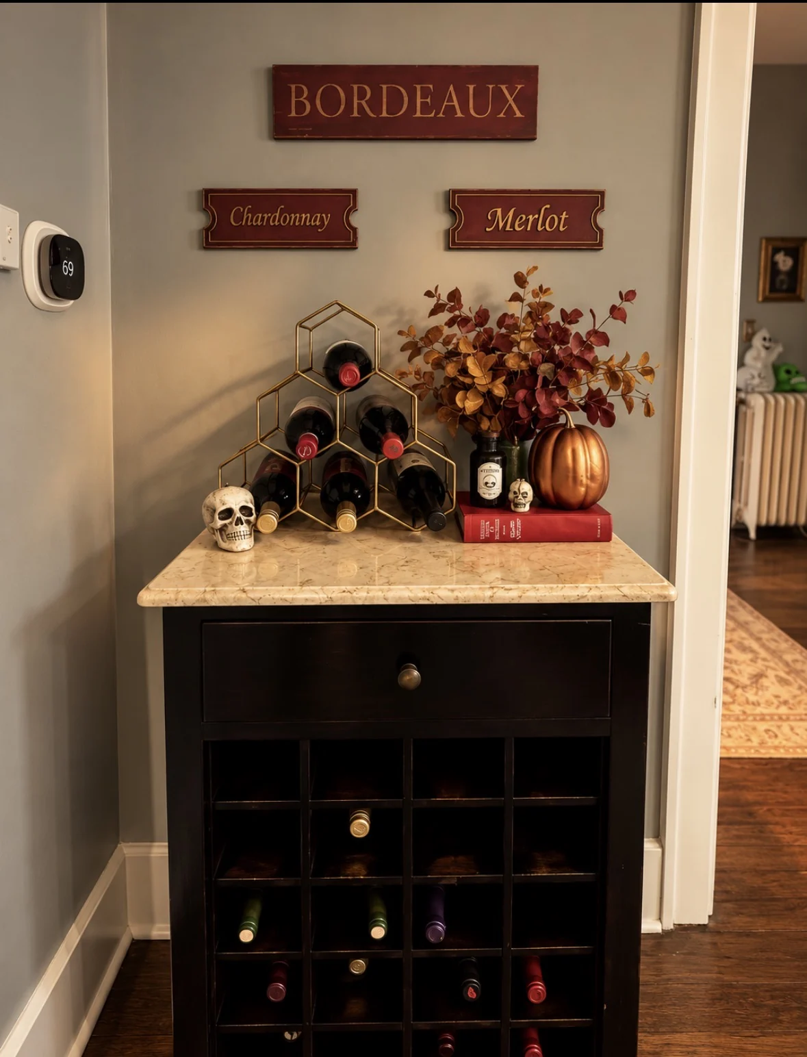 Wine nook styled for fall with bottles, leaves, a pumpkin, and small skull detail